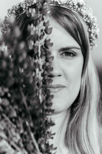 The photo of a woman's face covered with a lupine bouquet.