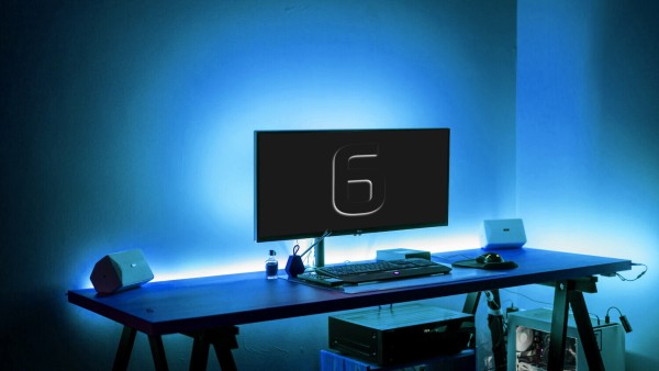 Computer with a KDE-blue glow in a darkened room. The screen is nearly entirely black, save for a the shining outline of the number 6.
