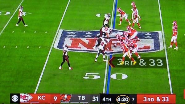A screenshot from Super Bowl LV shows Patrick Mahomes of the Kansas City Chiefs in the shotgun, lined up opposite the Tampa Bay Buccaneers dominating defense. The scoreboard across the bottom tells the story. 
KC 9–TB 31 with 4:20 remaining in the fourth quarter as the chief's face 3rd down and 33 situation.